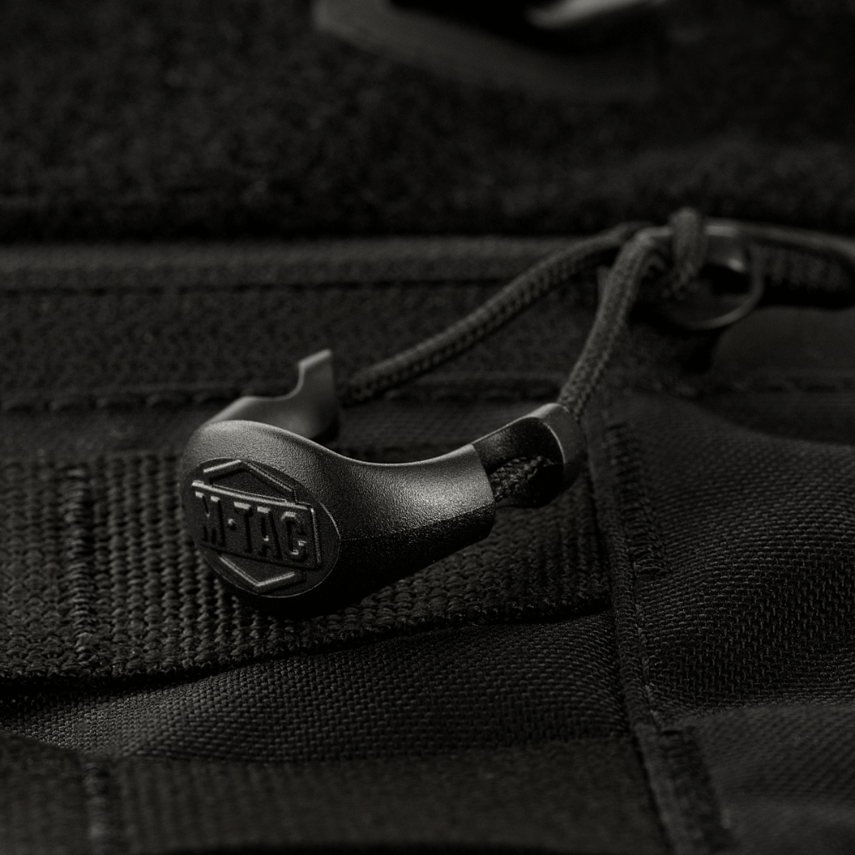 Yksityiskohta M-Tac Rygsæk Gen.II Elite Large -repusta kestävässä Cordura-materiaalissa, vahvat saumat ja vetoketjun vetimet näkyvissä.