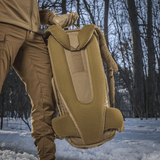 M-Tac Rygsæk Gen.II Elite Large, henkilö pitää reppua lumisessa metsässä; ergonominen muotoilu ja kestävät materiaalit näkyvät.