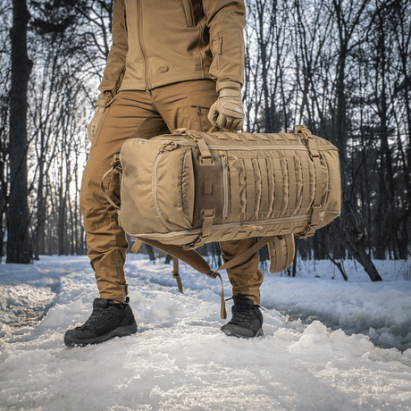 M-Tac Rygsæk Gen.II Elite Large, henkilö kantaa reppua lumisessa metsässä, valmistettu kestävästä Cordura-materiaalista ja siistillä muotoilulla.