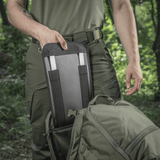 M-Tac Rygsæk Gen.II Elite Large, henkilö ottaa jotain repusta metsäympäristössä.