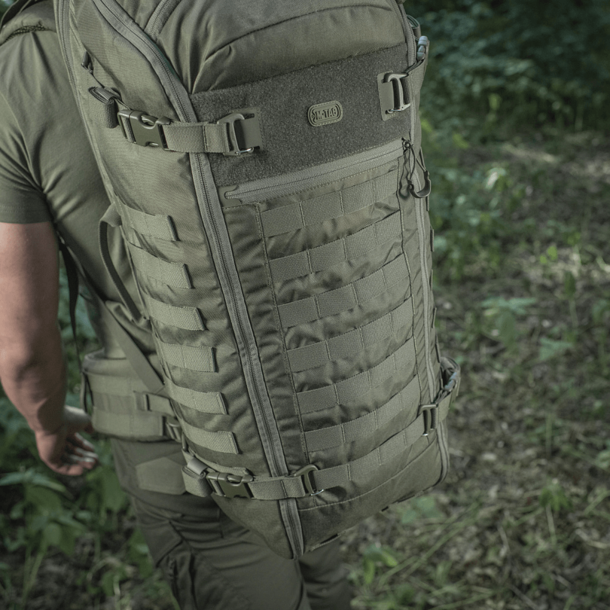 M-Tac Rygsæk Gen.II Elite Large, henkilö luonnossa; repun kestävä Cordura-muotoilu ja tilavat säilytysmahdollisuudet näkyvät.