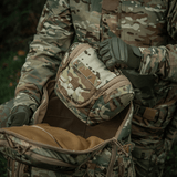 Henkilö ulkona kantaa M-Tac Toilettaske Elite Gen.II maastokuviossa.
