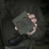 Henkilö pitelee M-Tac Double Mag Pouch Hook Backed Magazinea tumman taustan edessä