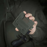 Henkilö pitelee M-Tac Double Mag Pouch Hook Backed Magazinea, sopii pistoolin lipuille ja multitoolille, kiinnitetty Velcrolla