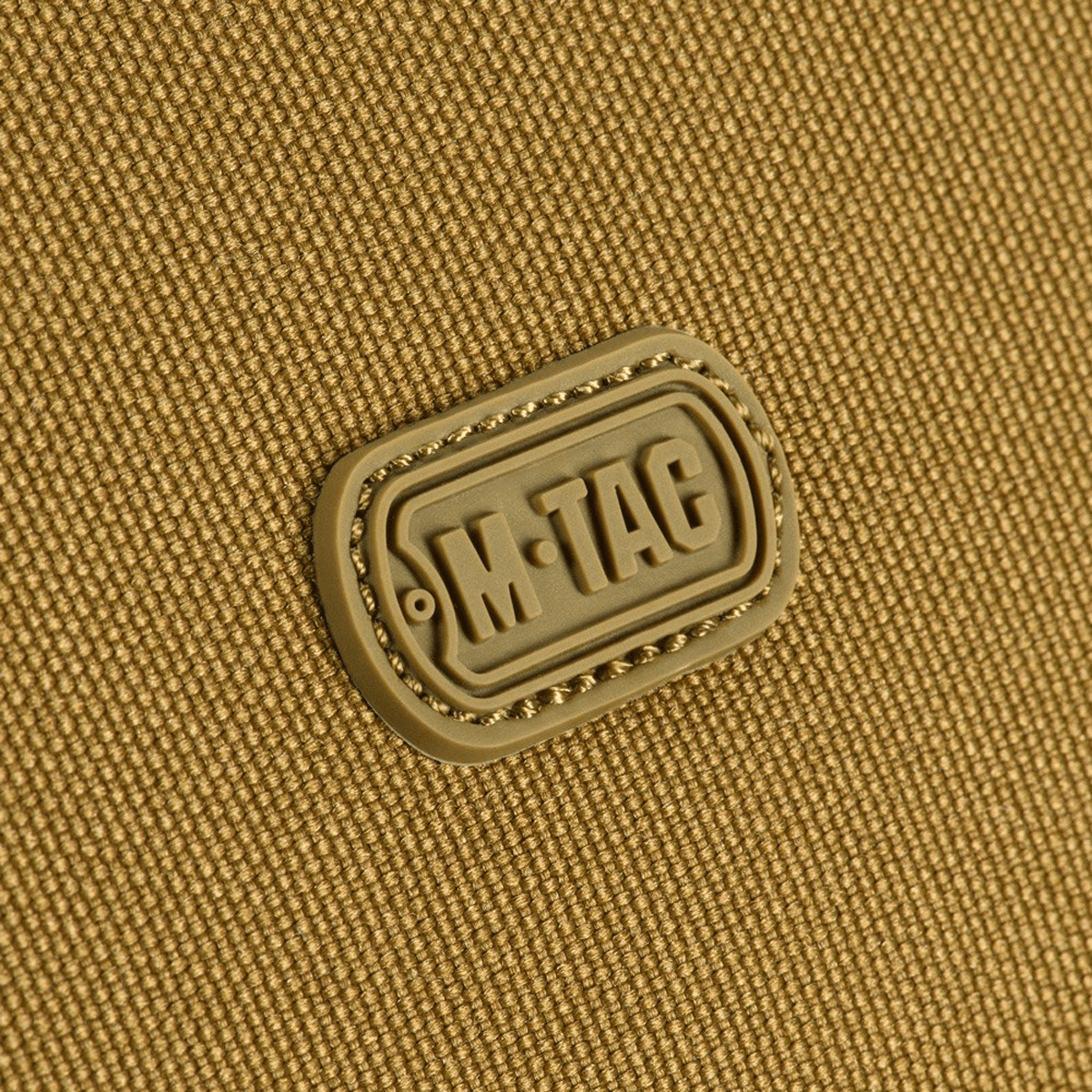 Lähikuva M-Tac-logosta kestävässä 600D polyesterissä PVC-pinnoitteella, sopii kompaktiksi säilytykseksi ja matkalle.