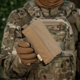 M-Tac Tourniquet Pouch Elastisk VELCRO Gen.II maastoympäristössä, pidetty taktisen varustuksen kantajan toimesta
