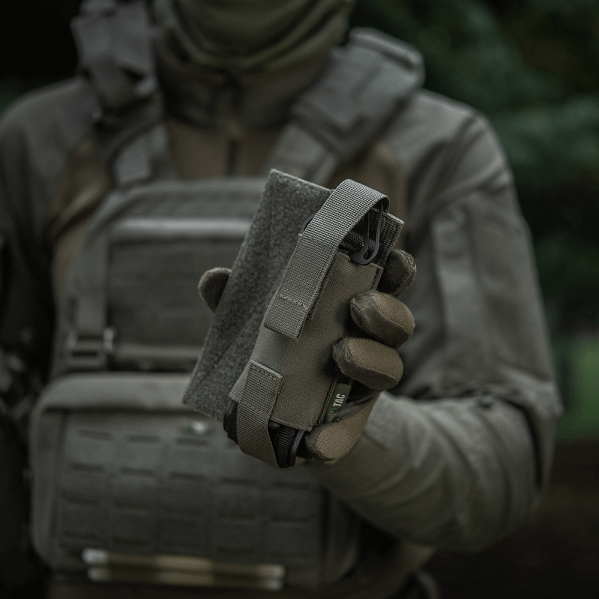 M-Tac Tourniquet Pouch Elastisk VELCRO Gen.II taktisen varusteisen henkilön kädessä nopeaan pääsyyn tourniquetiin
