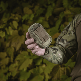 M-Tac PC Utility Pouch Elite camo kädessä, näyttää MOLLE-liitännän ja kestävän Cordura-materiaalin