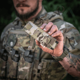 M-Tac Tourniquet Pouch Elastisk med MOLLE Gen.II camo-designilla, pidetään taktisten varusteiden kantajan toimesta, näyttää helpon pääsyn ja säilytyksen.