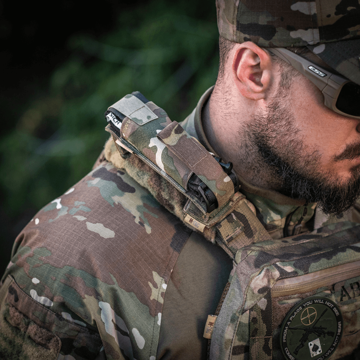Sotilas kantaa M-Tac Tourniquet Pouch Elastisk med MOLLE Gen.II:tä nopeaa pääsyä ja turvallista tourniquet-säilytystä varten MOLLE-varusteissa.