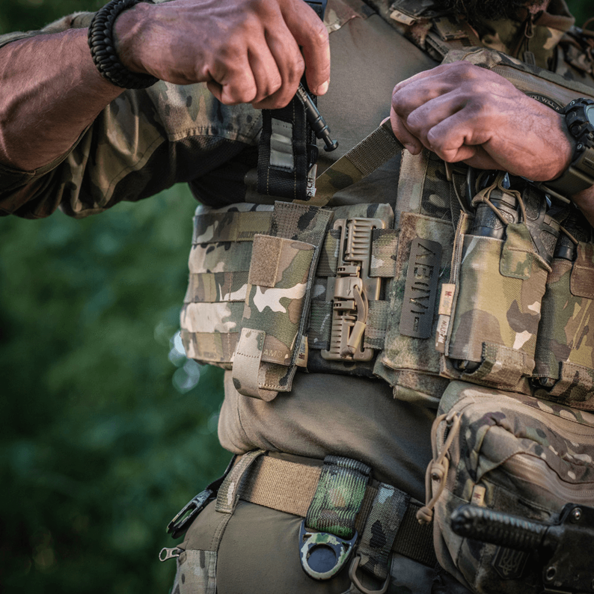 Sotilas kantaa M-Tac Tourniquet Pouch Elastisk med MOLLE Gen.II -koteloa sotilasvarusteissa luonnonympäristössä.