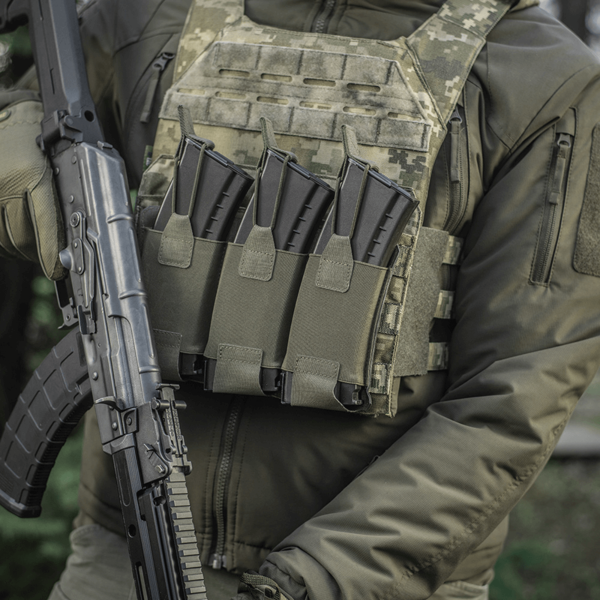 Henkilö pukeutuneena taktiseen liiviin, jossa M‑Tac Elastinen Triple Magazine Pouch Elite ja AK-lipat