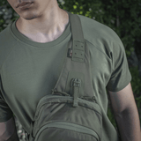 M‑Tac Cross Bag Elite Hex käytössä henkilöllä, joka pitää vihreää T-paitaa, sopii sekä arkeen että taktisiin varusteisiin.