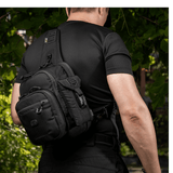 Mies kantaa mustaa M-Tac Smartphone Lomme Elite Large Hex -taskua, valmistettu CORDURA HEX -materiaalista, sopii puhelimille jopa 6,5 tuumaa.