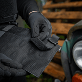 Henkilö säätää M‑Tac Front Panel Cuirass QRS:ää Woojin-koukuilla ja Velcrolla, Cordura 500D, sotilaskäyttöön.