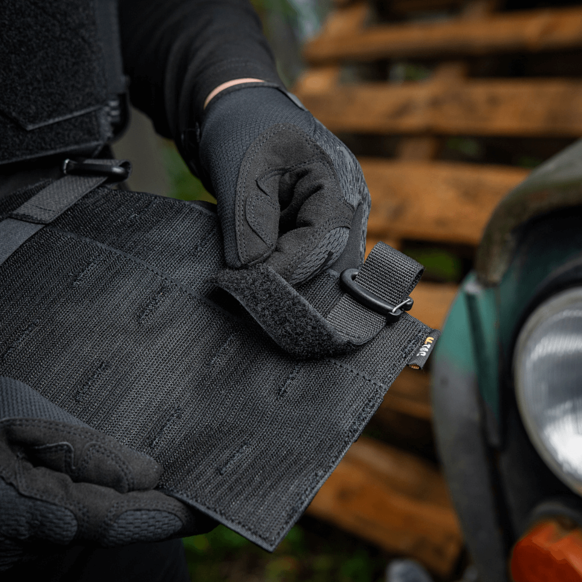 Henkilö säätää M‑Tac Front Panel Cuirass QRS:ää Woojin-koukuilla ja Velcrolla, Cordura 500D, sotilaskäyttöön.