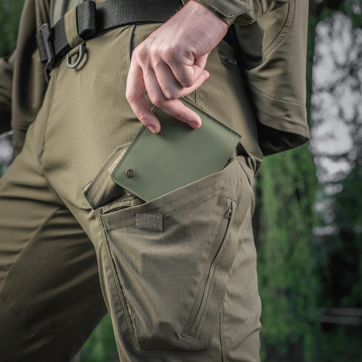 M-Tac Slim Elite Gen. II vihreänä vedetään housuntaskusta, näyttää kompaktin muodon ja modernin valmistusteknologian.