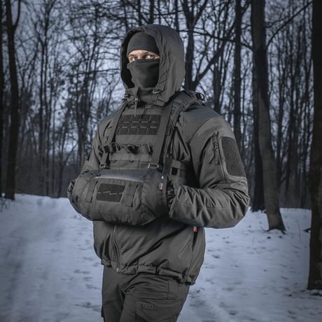 Henkilö käyttää M-Tac taktista käsilämmitintä Elite lumisessa metsässä, pitää kädet lämpiminä kylmässä säässä.