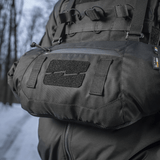 Henkilö käyttää M-Tac taktista käsilämmitintä Elite lumisessa metsäympäristössä, valmistettu kestävästä Cordura 500D:stä pehmeällä Polartec®-fleecevuorella.