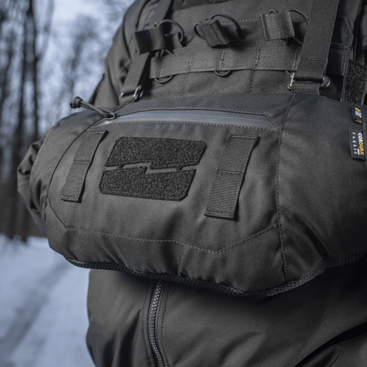 Henkilö käyttää M-Tac taktista käsilämmitintä Elite lumisessa metsäympäristössä, valmistettu kestävästä Cordura 500D:stä pehmeällä Polartec®-fleecevuorella.