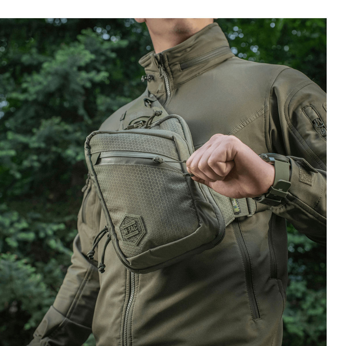 Henkilö kantaa M-Tac Sling Pistoltaske Elite Hexitä ulkona mukavassa ja kestävässä laukussa, säädettävä hihna ja tilavat osastot.