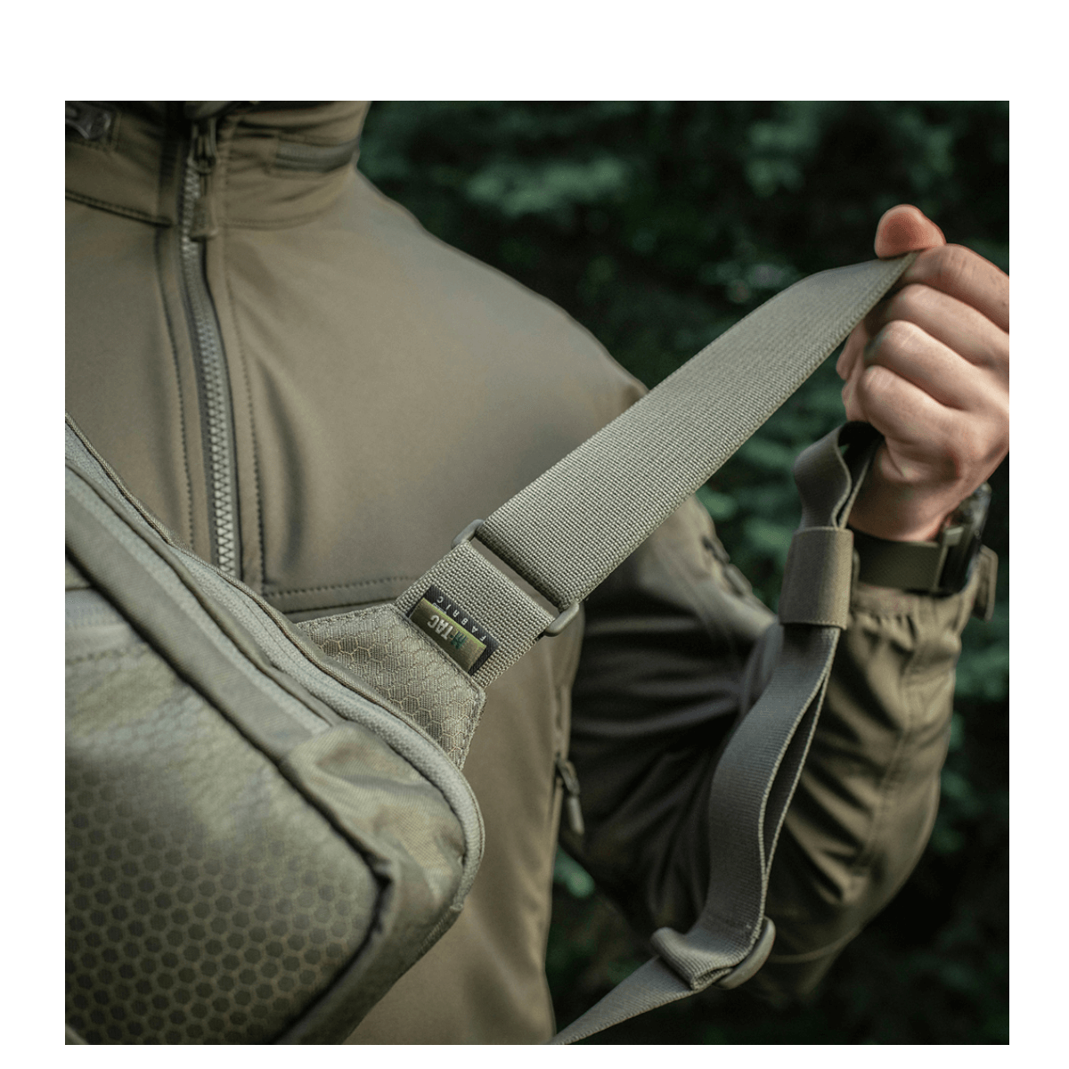 Mies kantaa M-Tac Sling Pistoltaske Elite Hexiä säädettävällä olkahihnalla Cordura-materiaalista.