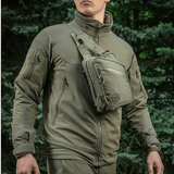 Mies, jolla on M-Tac Sling Pistoltaske Elite Hex, monipuolinen ja tyylikäs laukku piilotetulle aseelle, valmistettu Cordura 1000D -materiaalista.