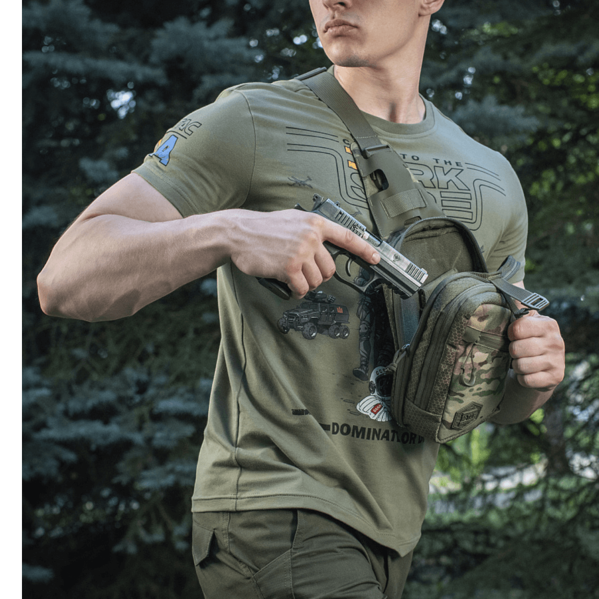 Mies kantaa M-Tac Sling Pistoltaske Elite Hexiä piilotetun aseen kanssa metsässä.