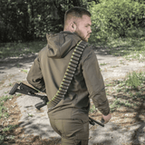 Metsästäjä pukeutuneena M-Tac Bandolier Eliteen ammuksineen metsäympäristössä.