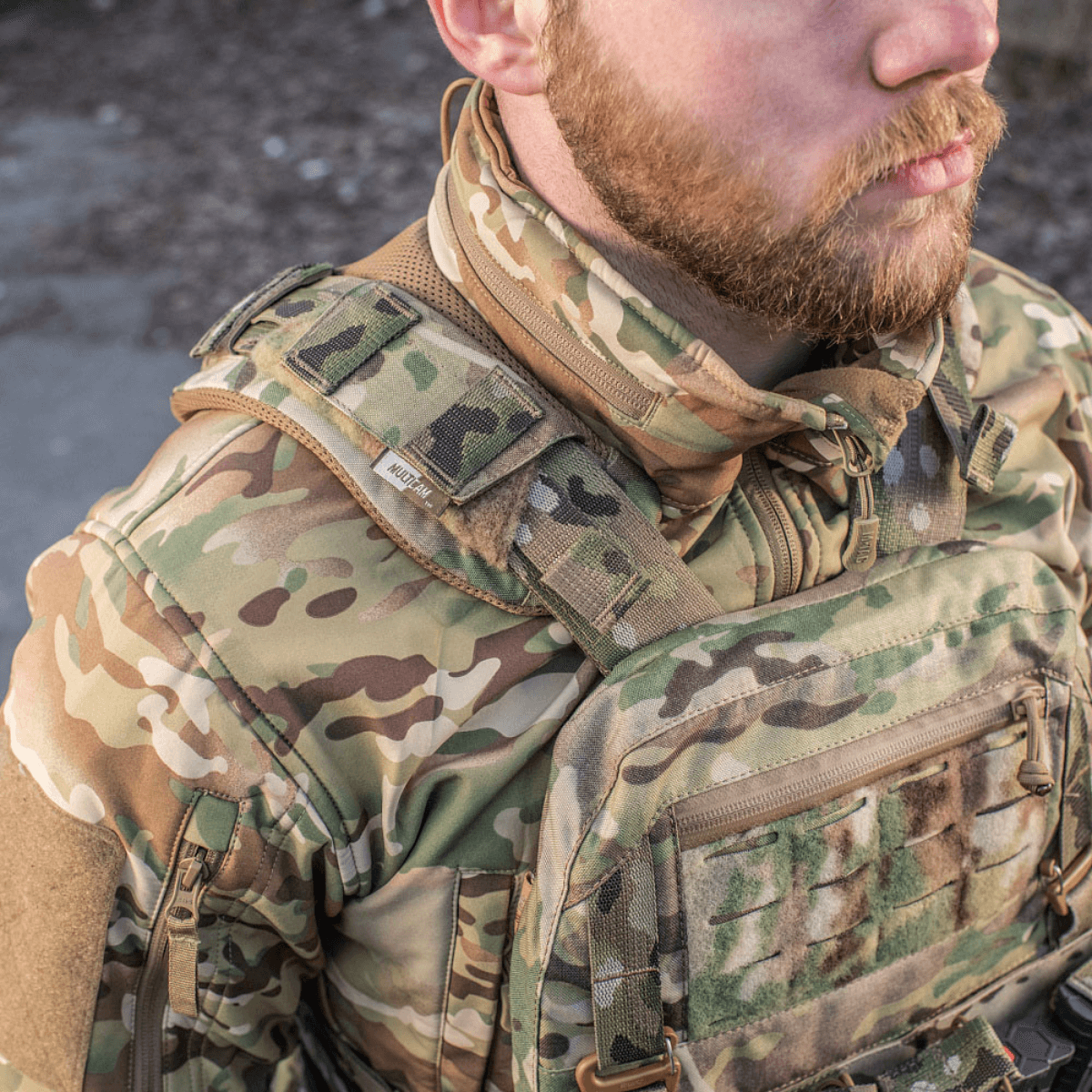 Mies pukeutuneena M-Tac olkapääpehmusteeseen Plate Carrier Cuirass QRS:lle kulutusta kestävästä Cordurasta, Velcro-kiinnitys maastovarustukseen.