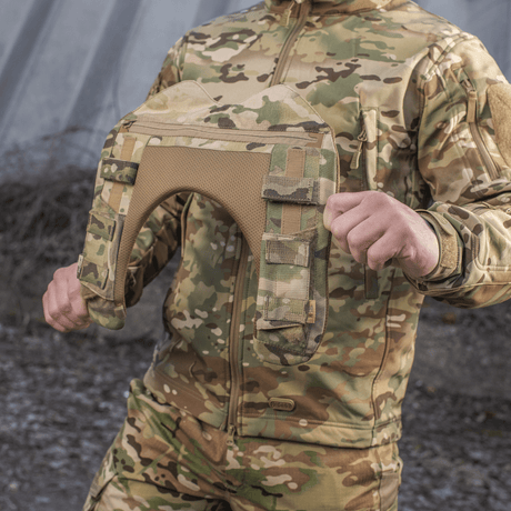 Henkilö, jolla M-Tac olkapääpehmuste Plate Carrier Cuirass QRS:lle maastokuvioituna, suunniteltu mukavuuteen ja painonjakoon.