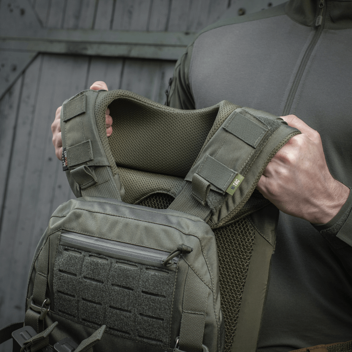 Henkilö esittelee M-Tac olkatyynyn Plate Carrier Cuirass QRS, korkealaatuinen Cordura ja 3D-mesh mukavuuteen ja tuuletukseen