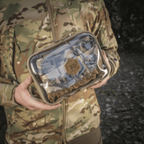 M-Tac Utility Organizer Slim Elite maastokuvioituna, henkilön pitämä, näyttää kestävän Cordura 500D:n ja PVC-kalvon nopeaan tunnistukseen.
