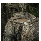 Henkilö camokuvioisessa asussa kantaa M-Tac Mission Pack Elitea MOLLE LASER CUT -järjestelmällä metsässä ergonomista toimivuutta varten.
