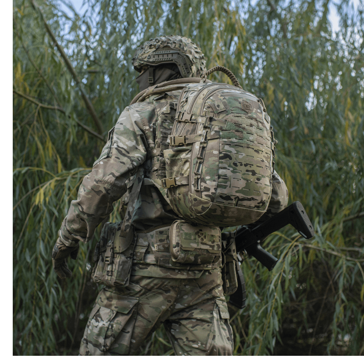 Sotilas kantaa M-Tac Mission Pack Elite -reppua camo-kuvioituna luonnossa.