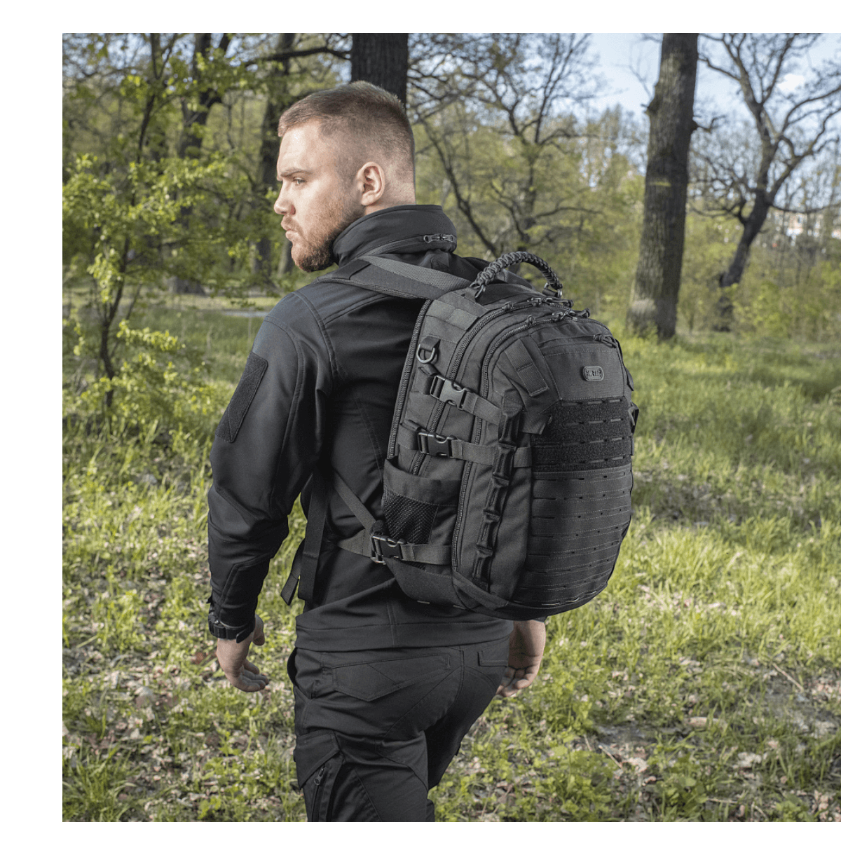 Mies kantaa M-Tac Mission Pack Elite -reppua luonnossa, korostaen ergonomista muotoilua ja Cordura 1000D -materiaalia.