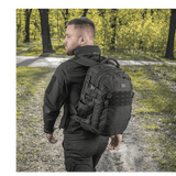 Mies kantaa M-Tac Mission Pack Elite -reppua metsässä, valmistettu Cordura 1000D:stä ja varustettu MOLLE LASER CUT-systemillä.