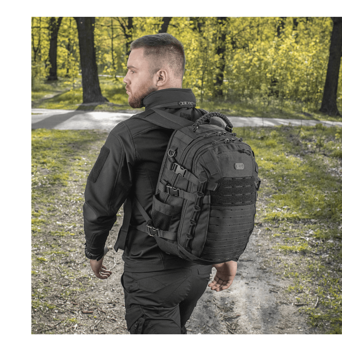Mies kantaa M-Tac Mission Pack Elite -reppua metsässä, valmistettu Cordura 1000D:stä ja varustettu MOLLE LASER CUT-systemillä.