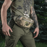 Mies kantaa M‑Tac Elite Hex -vyölaukkua camo-kuosissa, sopii taktiseen käyttöön, Cordura 500D ja YKK-vetoketjut.