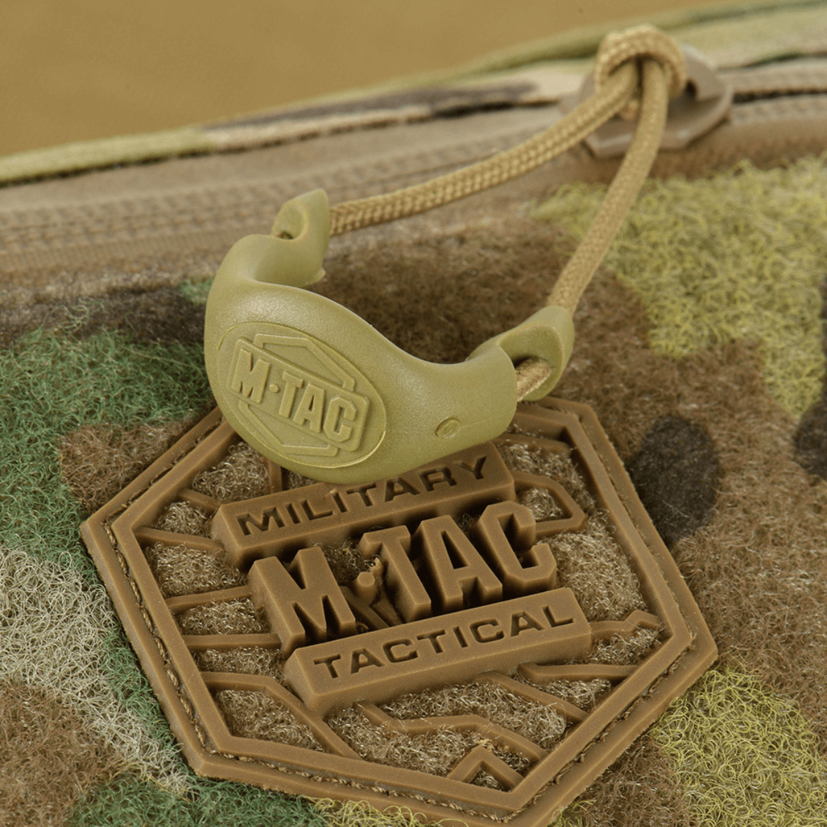 M‑Tac Elite Hex -lähikuva logosta ja vetoketjun yksityiskohdista taktillisessa muotoilussa, sopii arkeen tai varustukseen.