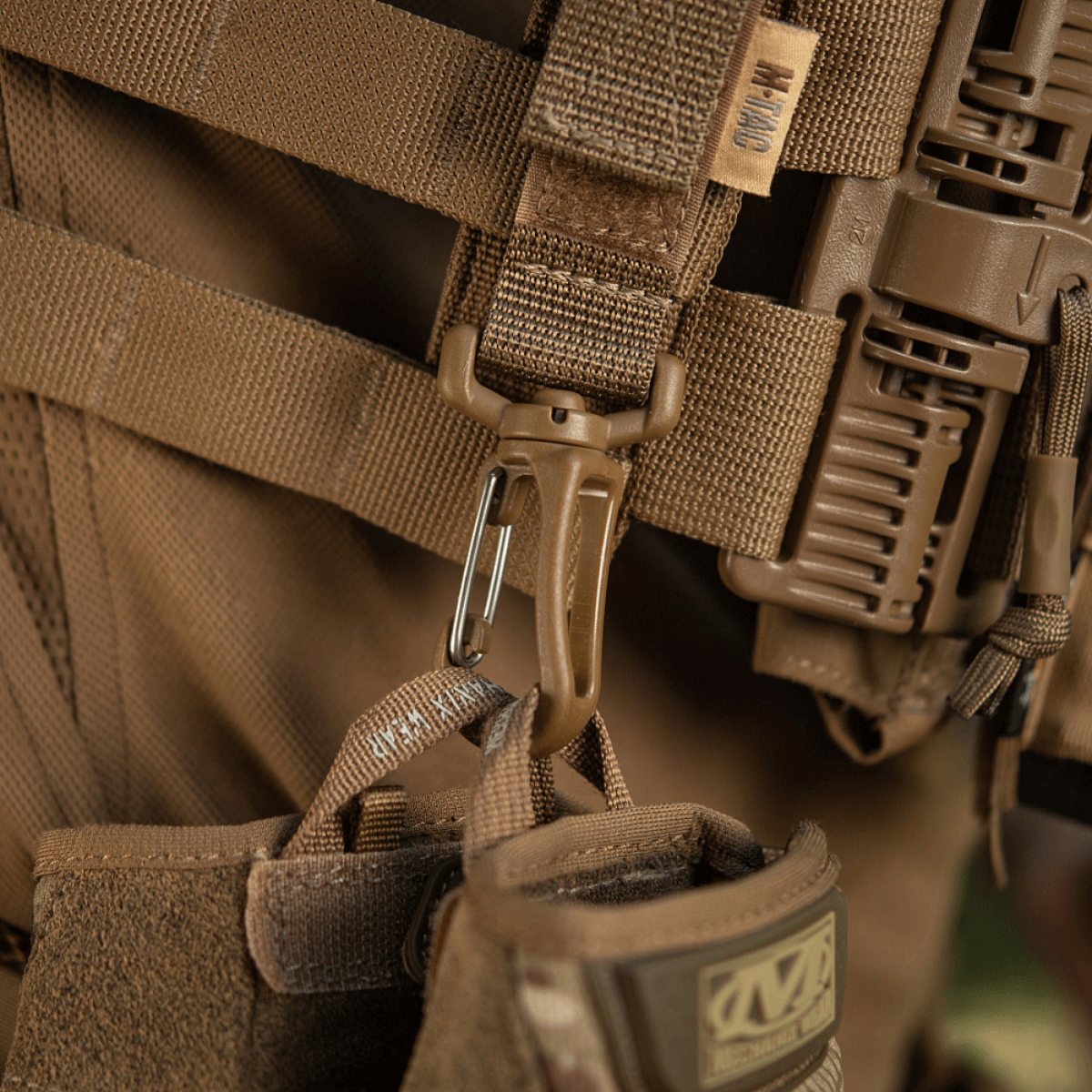 M-Tac karabiinihaka-lisävaruste kiinnitetty taktiseen MOLLE-reppuun, helppo kiinnitys Velcro-remmillä ja kevyt muotoilu.