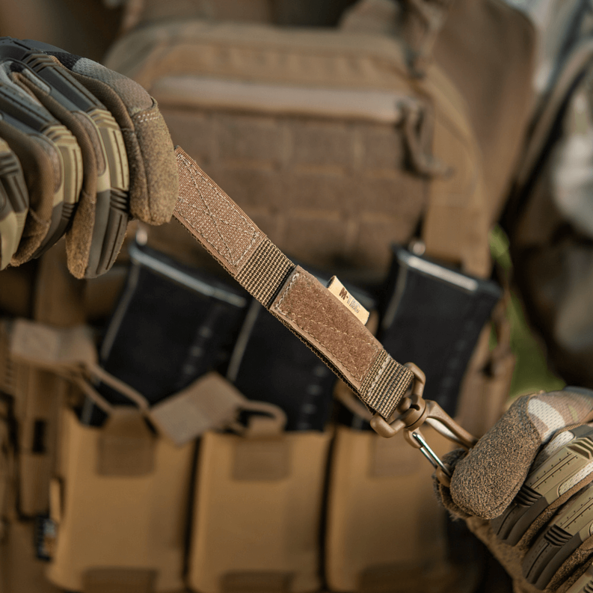 M-Tac karabiinihaka-lisävaruste kiinnitetty taktiseen MOLLE-liiviin Velcro-remmillä varusteiden kiinnitykseen.