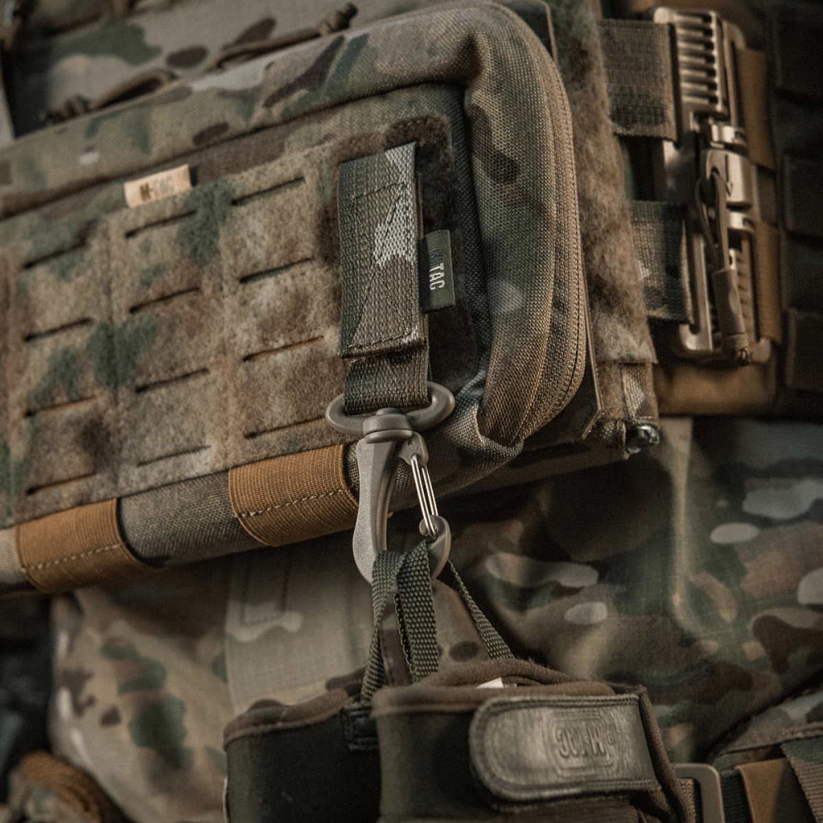 M-Tac karabiinihaka-lisävaruste kiinnitetty taktiseen MOLLE-reppuun, helppo avata ja säädettävä Velcro-remmi.