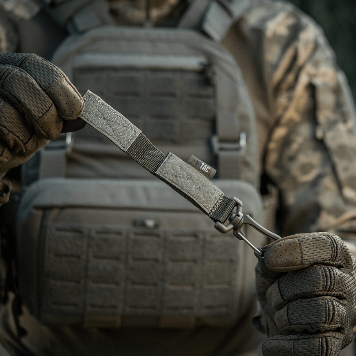 M-Tac karabiinihaka-lisävaruste kiinnitetty taktiseen MOLLE-järjestelmään säädettävällä Velcro-remmillä.