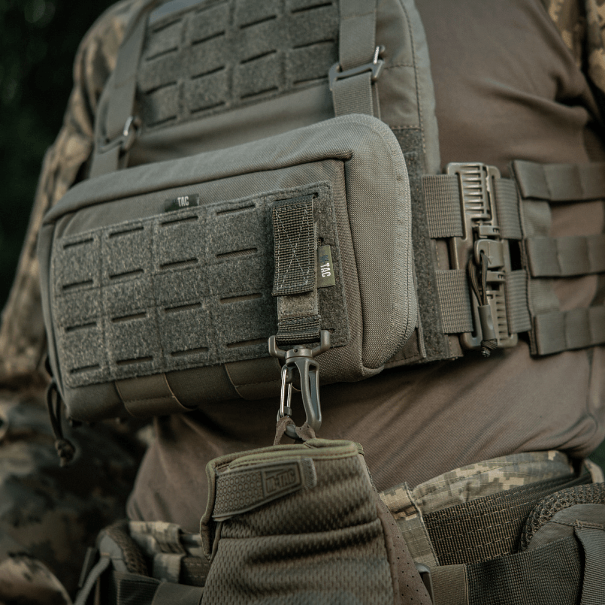 M-Tac karabiinihaka-lisävaruste kiinnitetty taktiseen MOLLE-liiviin, ihanteellinen varusteiden kiinnittämiseen ja säädettävyyteen.