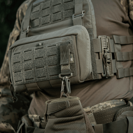 M-Tac karabiinihaka-lisävaruste kiinnitetty taktiseen MOLLE-liiviin, ihanteellinen varusteiden kiinnittämiseen ja säädettävyyteen.