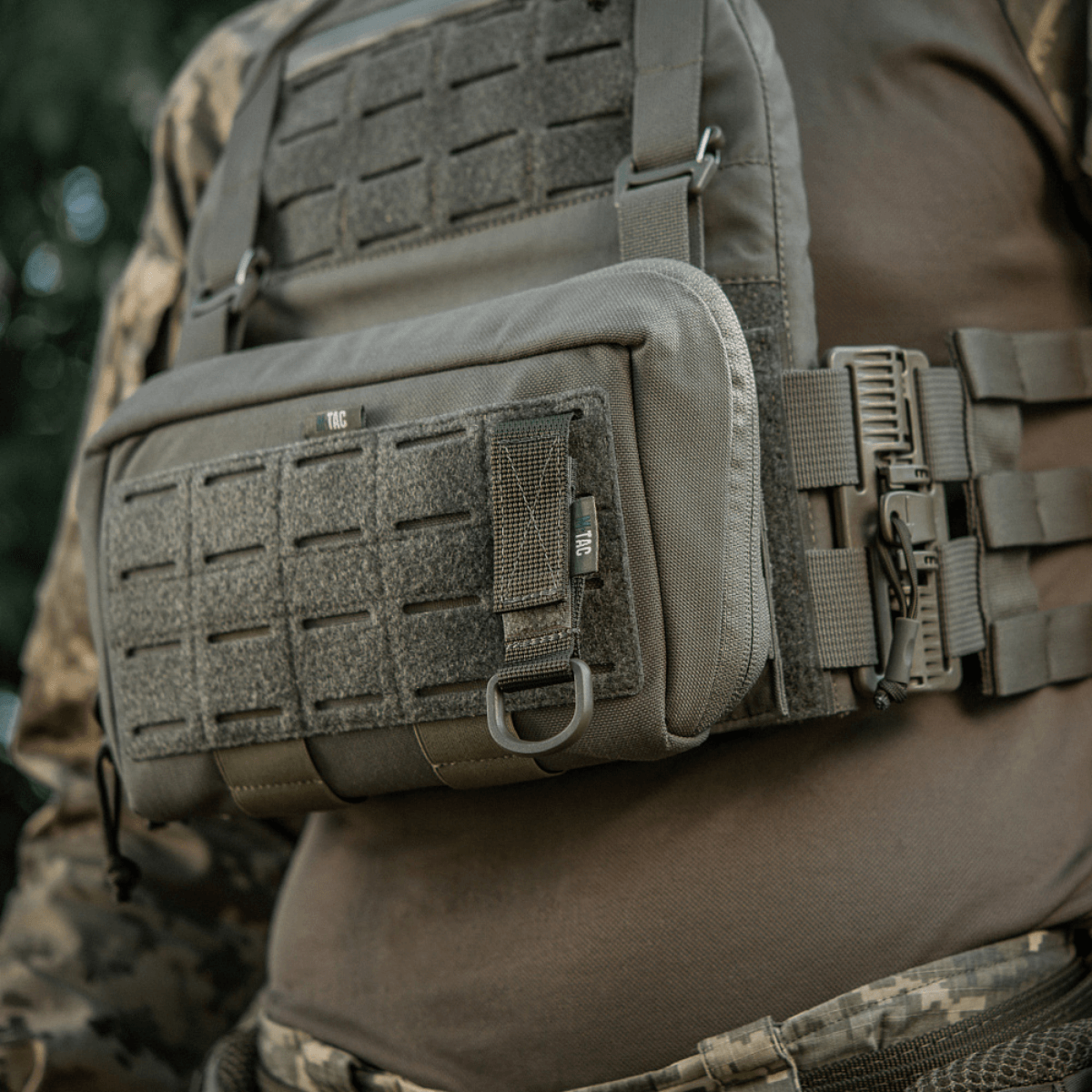 M-Tac-kiinnike D-renkaalla asennettuna taktiseen liiviin MOLLE-järjestelmän avulla varusteiden turvalliseen ripustukseen Velcro-sulkimella.