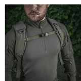Mies pukeutuneena M-Tac Mission Rygsæk Elite Hex -reppuun, Cordura 1000D, ergonominen muotoilu ja MOLLE LASER CUT -järjestelmä metsäympäristössä.