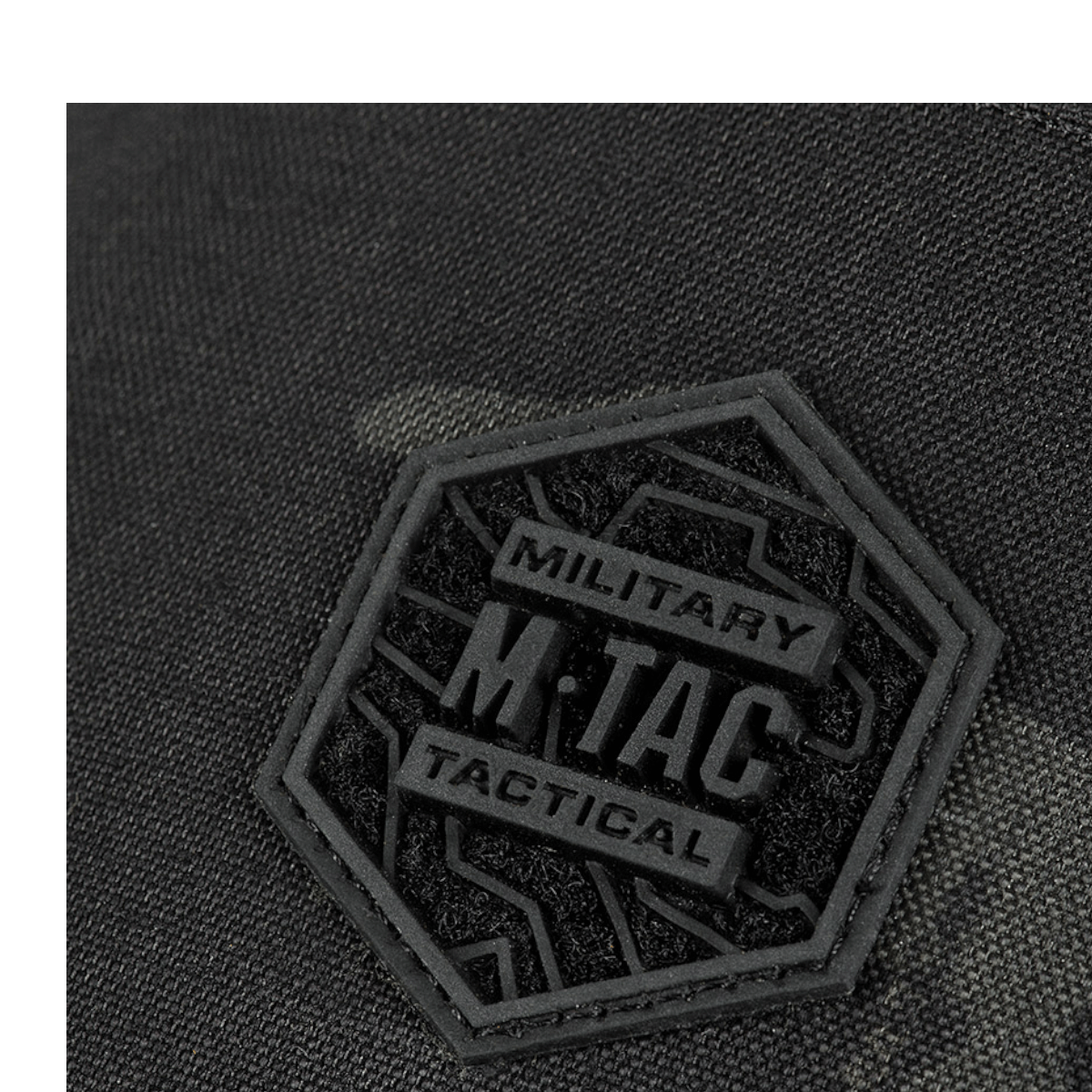 M-Tac Cross Taske Slim Elite Hex -logo laukussa kulutusta kestävästä Cordura-materiaalista, lähikuva M-Tac-merkistä.