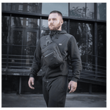 Mies kantaa M-Tac Cross Taske Slim Elite Hex -laukkua, tyylikäs ja toimiva laukku Cordura-materiaalista, varusteina YKK ja Woojin.